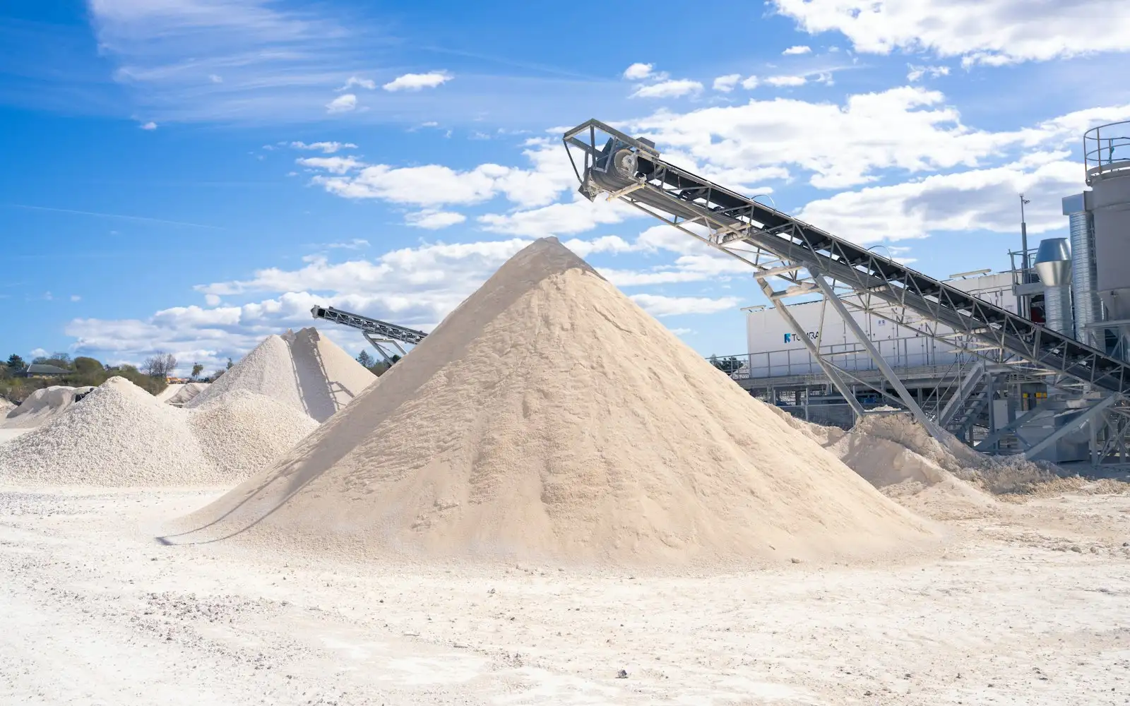 Sand stockpiles and conveyors at an aggregate pit